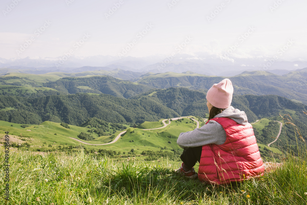 young woman is sitting against background of mountains . travel, hiking, journey, outdoor recreation