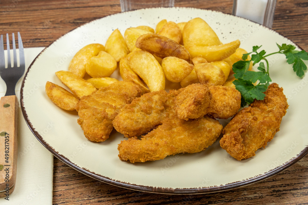potato and cooked chicken nuggets in a plate on a table potato and cooked chicken nuggets in a plate on a table