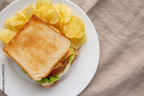 Homemade Fried Bologna and Cheese Sandwich with Chips on a Plate, top view. Flat lay, overhead, from above. Copy space.