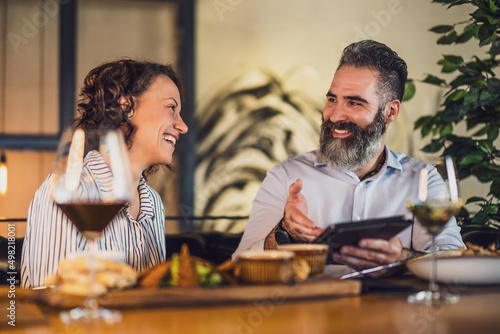 Happy couple is sitting at restaurant. They are having dinner with wine and spending nice time together.