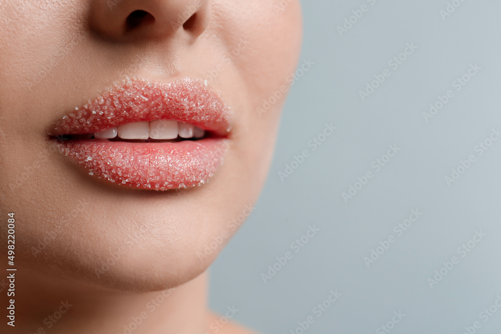 Fototapeta premium Closeup view of woman with lips covered in sugar on light grey background. Space for text