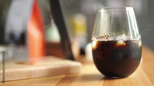 cube of ice add on glass of americano coffee, home brewing process 