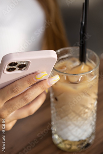 Close up of a woman's hand using smartphone in cafe bar