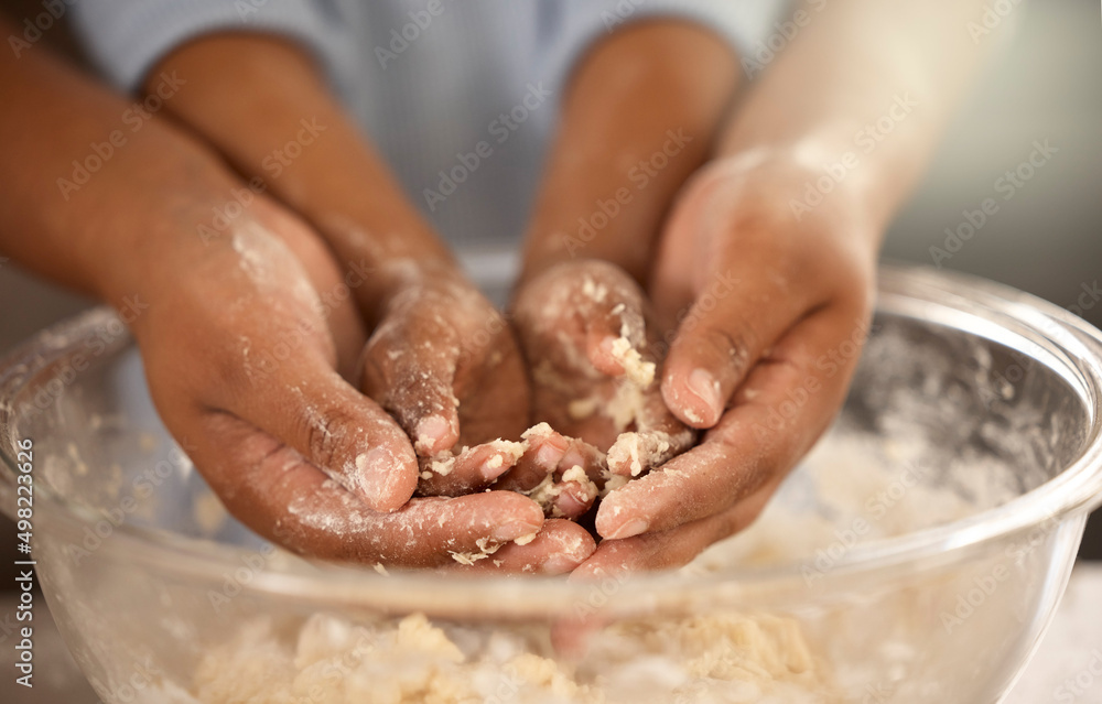 Kids learn by getting dirty. Cropped shot of an unrecognizable father and son covering their hands in cookie batter while baking together at home.