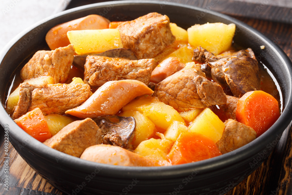 Filipino pork menudo traditionally consists of chunks of pork that is stewed in a tomato sauce close up in the plate on the table. Horizontal Filipino pork menudo traditionally consists of chunks of pork that is stewed in a tomato sauce close up in the plate on the table. Horizontal