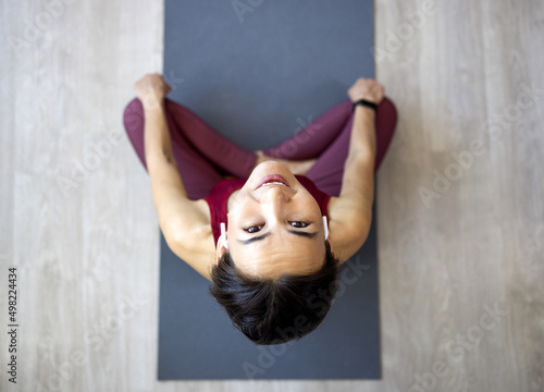 Attractive Asian woman practices the concept of yoga, sits in an exercise on a yoga mat, Balasana pose, exercises, wears sportswear, sleeveless T-shirt and pants, full length, white attic background. photo