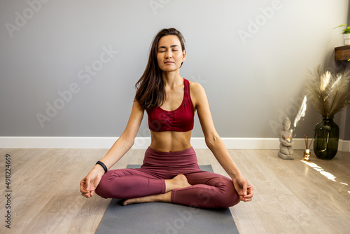 Asian attractive healthy woman practicing yoga in the living room in the morning. Feel happily refreshed during the activity, in shape, while doing yoga meditation in the condominium. 