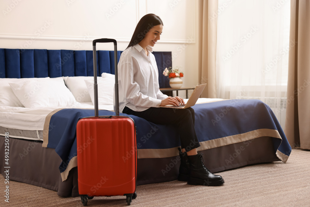 Beautiful young business woman working with laptop on bed in hotel room Beautiful young business woman working with laptop on bed in hotel room
