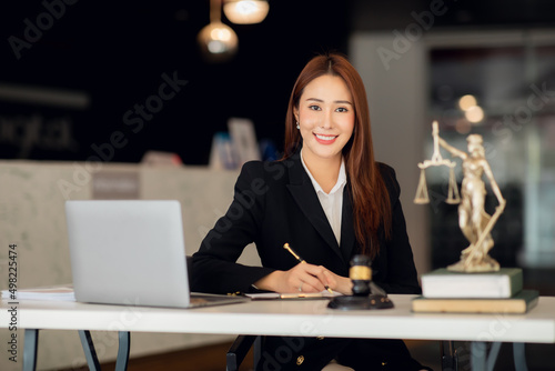 Attractive young lawyer in office Business woman and lawyers discussing contract papers with brass scale on wooden desk in office. Law, legal services, advice, Justice and real estate concept. photo