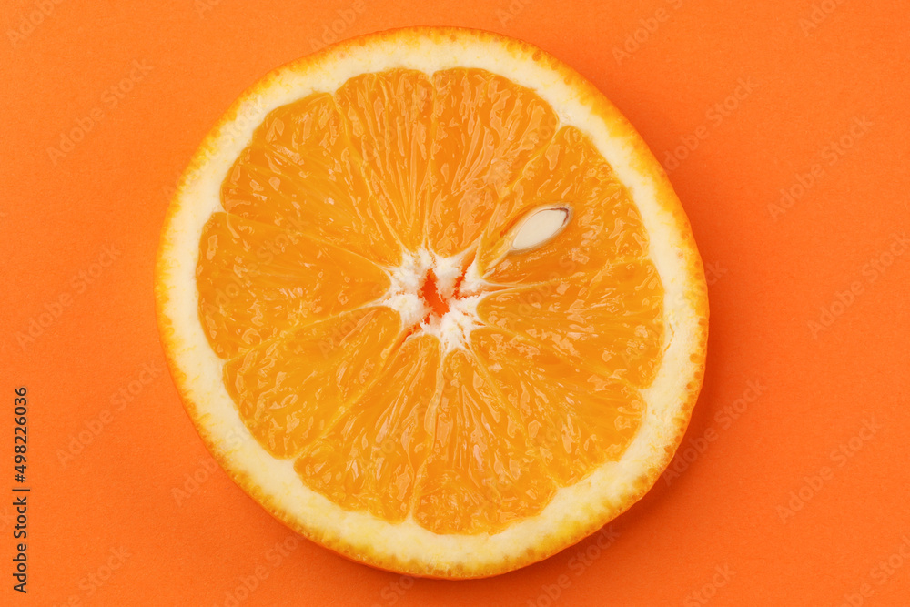 Round slice of orange with pit on orange background Round slice of orange with pit on orange background