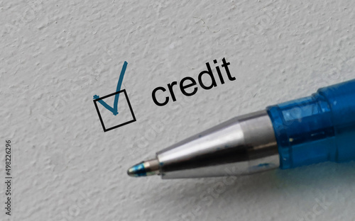 check mark on the word credit and blue pen. Closeup, concept