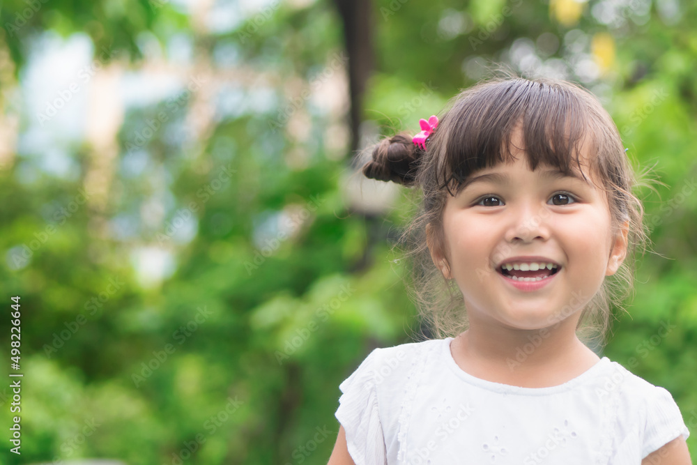 Happy cute little girl happily smiling in green summer park Happy cute little girl happily smiling in green summer park
