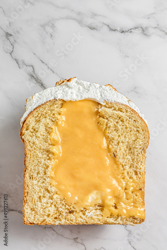 An Easter cake with meringue in top cut in half with lemon curd cream liquid filling on light grey marble background photo