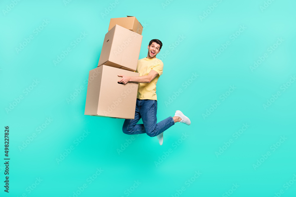 Full size photo of cool brunet guy jump with box wear t-shirt jeans sneakers isolated on turquoise background Full size photo of cool brunet guy jump with box wear t-shirt jeans sneakers isolated on turquoise background
