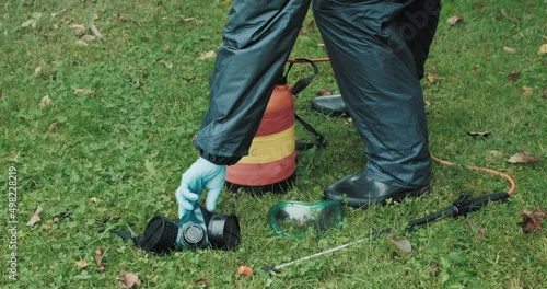 Lawn treatment with insecticides and toxins from ixodic mites and other blood sucking parasites. A man in a protective suit sprays poison on the grass photo