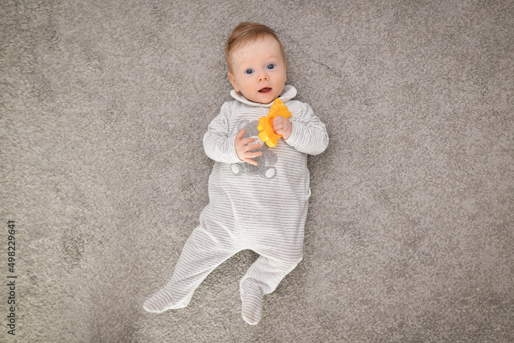 High angle view of a happy cute baby lying on carpet at home. Pretty young boy playing. High angle view of a happy cute baby lying on carpet at home. Pretty young boy playing.