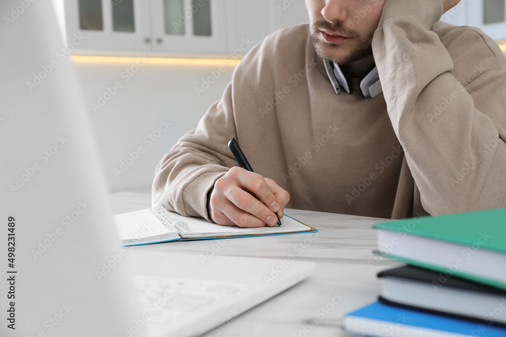 Young man using modern laptop for studying in kitchen, closeup. Distance learning Young man using modern laptop for studying in kitchen, closeup. Distance learning