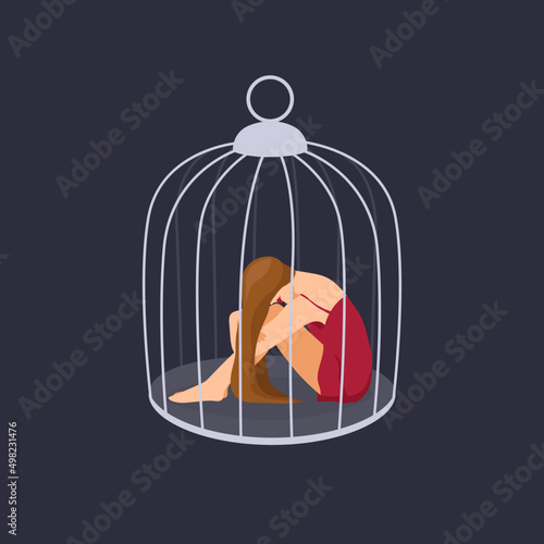 Woman hugging her knees sitting inside of the cage. Concept of captivity, helplessness and depression
