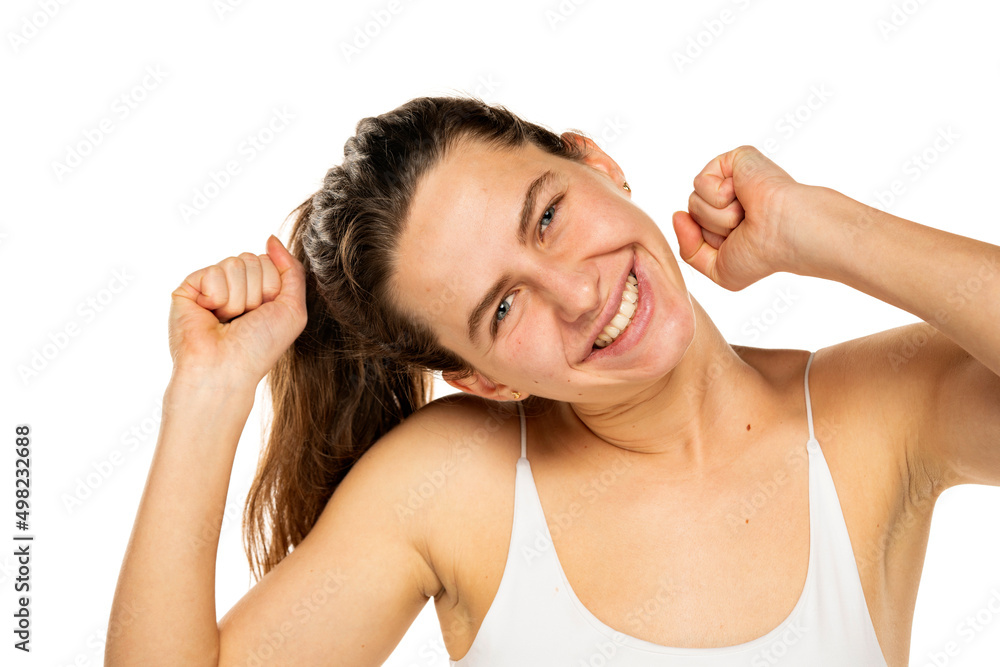 Portrait of cheerful positive young woman with raised fists looking at camera isolated on white background