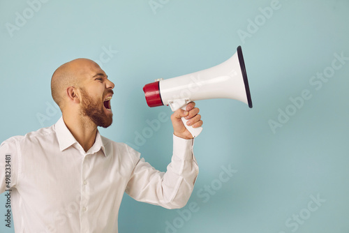 Young man isolated on green studio background scream in loudspeaker make sale announcement to public. Male hold megaphone shout advertise inform big sale deal or promotion discount. Advertisement.