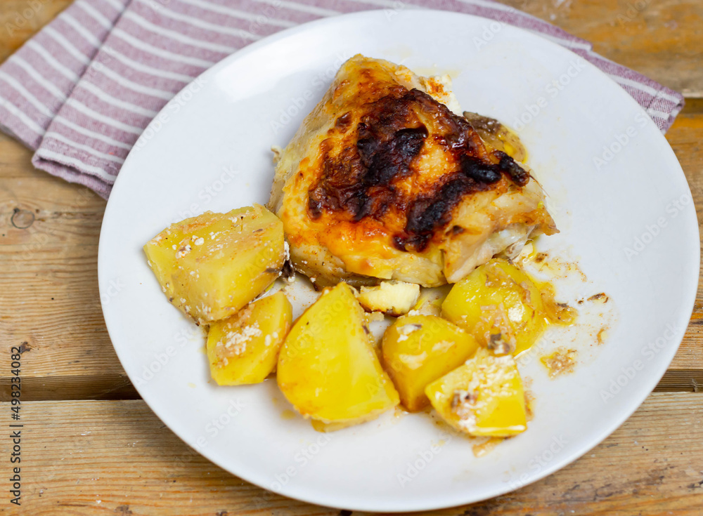 Chicken and potatoes on a white plate with a napkin. View from above. Chicken and potatoes on a white plate with a napkin. View from above.