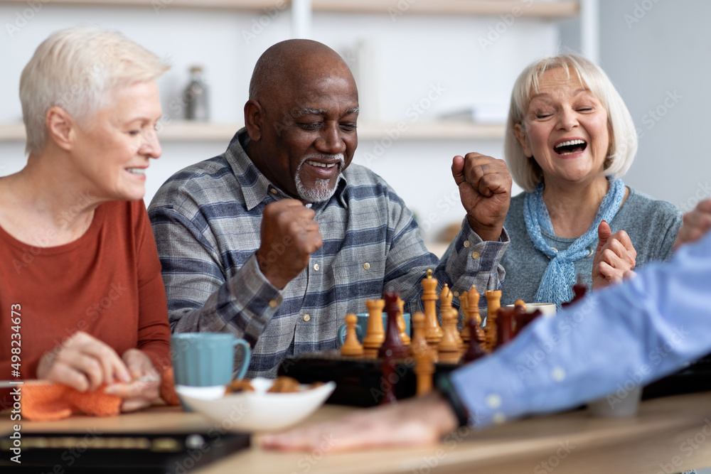Emotional black man playing chess with multiracial friends Emotional black man playing chess with multiracial friends
