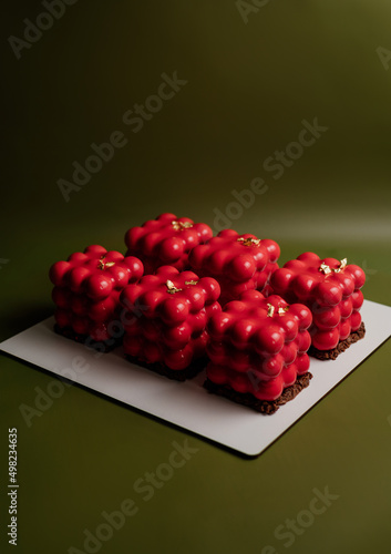 Beautiful mousse cakes covered with mirror shiny glaze. Green back ground. The skill of the pastry chef.