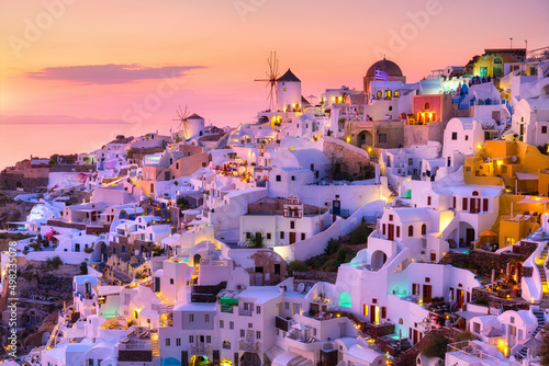 Fototapeta Naklejka Na Ścianę i Meble -  Oia village, Santorini, Greece. View of traditional houses in Santorini. Small narrow streets and rooftops of houses, churches and hotels. Landscape during sunset.