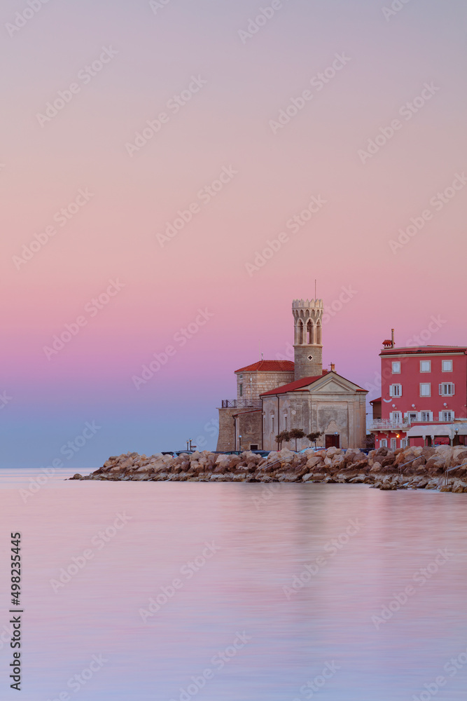 Piran, Slovenia. Cityscape image of Piran, Slovenia with historical church and lighthouse at sunrise.