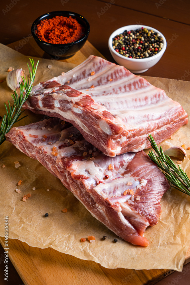 Raw ribs with rosemary on a wooden board Raw ribs with rosemary on a wooden board