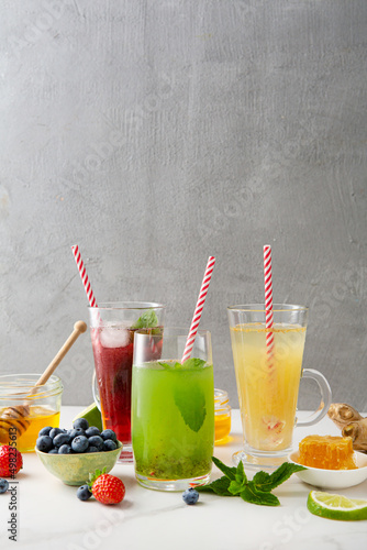 Summer fruit and berry drinks with ice lemonade on light surface