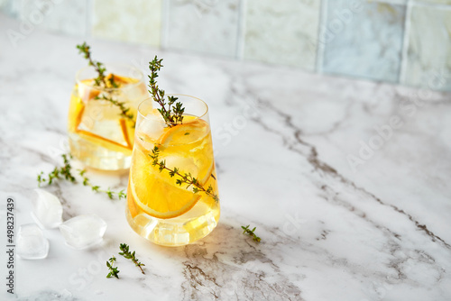 Refreshing cocktail with ice, orange and thyme. Refreshing summer homemade alcoholic or non-alcoholic cocktail or mocktail, or Detox infused flavored water