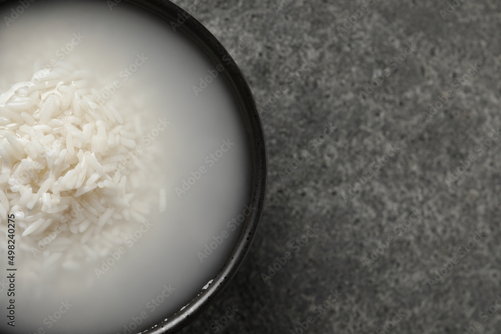 Bowl with rice soaked in water on grey table, top view. Space for text Bowl with rice soaked in water on grey table, top view. Space for text