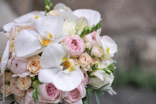 Wedding bouquet on gray stone background. Bridal bouquet composed of roses  freesia  peony and phalaenopsis orchids. Wedding day.