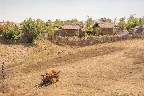 Rural landscape with a small village and a wooden cart