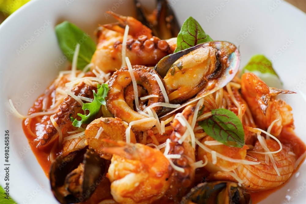 Seafood pasta - shrimp, clams and octopus served with cheese and basil leaves and red sauce Seafood pasta - shrimp, clams and octopus served with cheese and basil leaves and red sauce