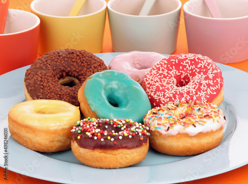 Tablou canvas Variety of colorful donuts plate on party table background.