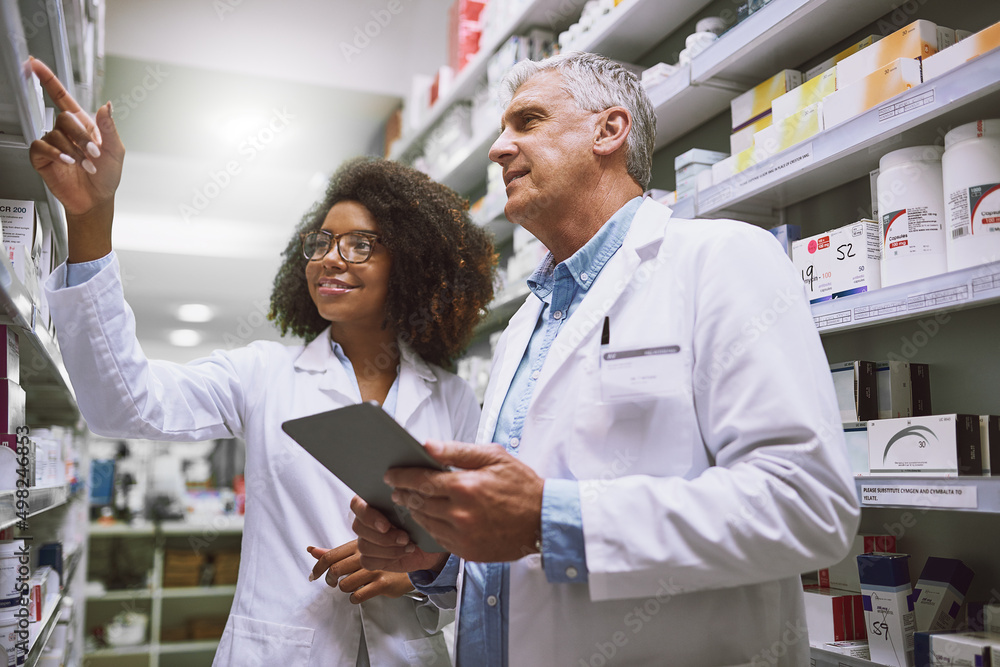 Obraz premium We need more of this meds. Shot of two focused pharmacist walking around and doing stock inside of a pharmacy.