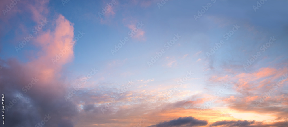 Fototapeta premium blue sky background, framed with pink yellow and orange clouds, sunset scenery