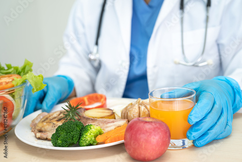 Nutritionist doctor holding various healthy fresh vegetables for patient.