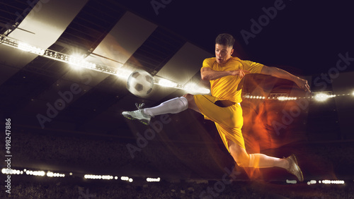 Bright dynamic collage with professional soccer, football player kick the ball in jump at dark night stadium with flashlights. Sport, competition, championship