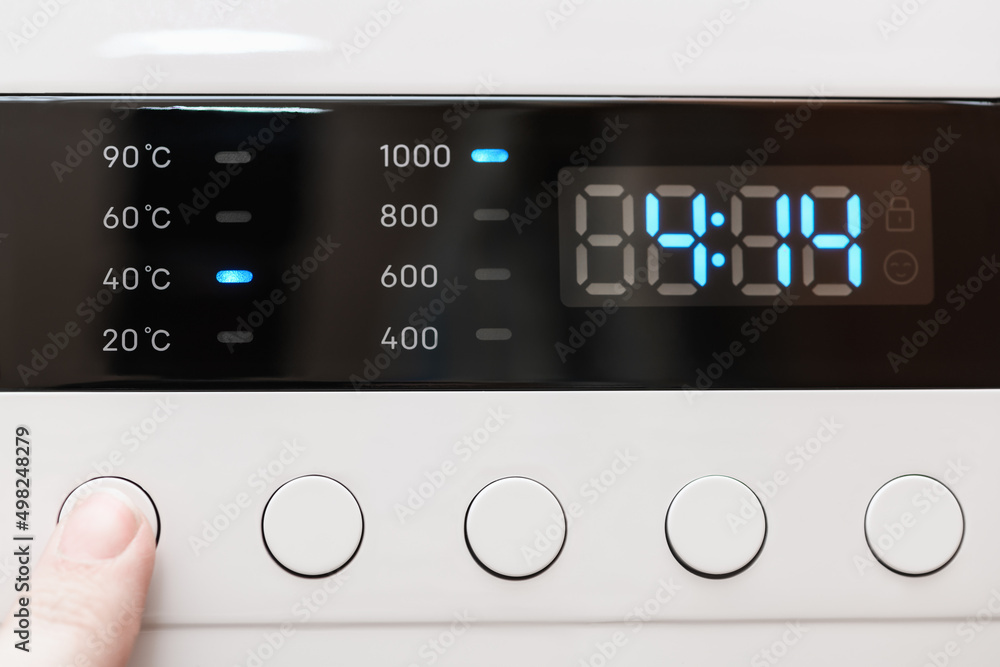 Washing machine display close up ,time remaining four hour 14 minutes during washing process. Finger selects wash mode. Abstract laundry programming backdrop Washing machine display close up ,time remaining four hour 14 minutes during washing process. Finger selects wash mode. Abstract laundry programming backdrop