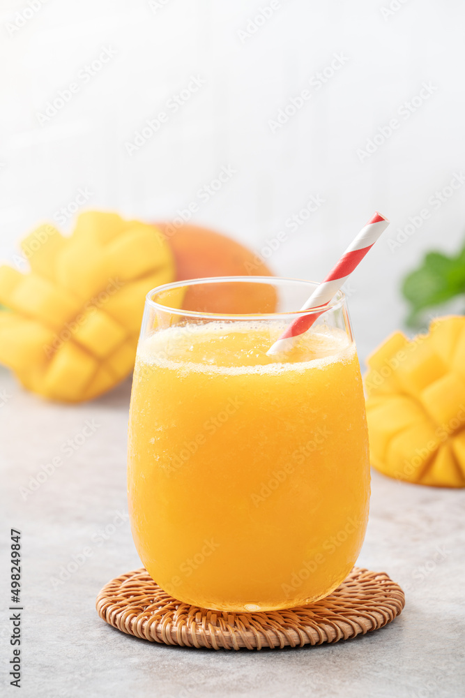 Fototapeta premium Fresh beautiful delicious mango juice smoothie in a glass cup on gray table background.