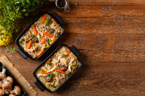 Photography Chicken casserole. Served in black pots.