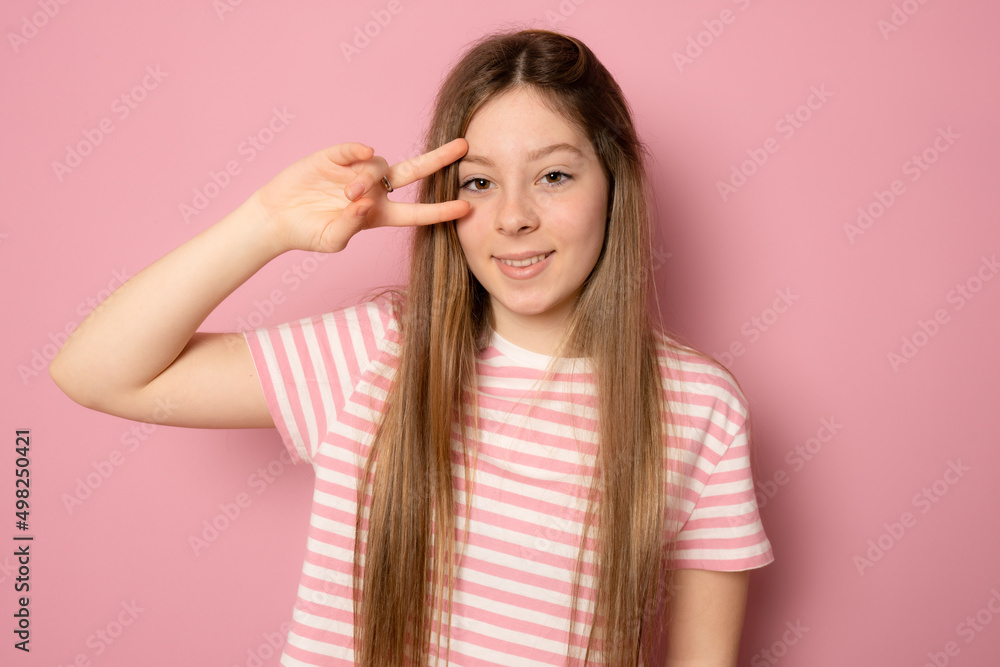 Fototapeta premium Young beautiful blonde woman wearing casual striped t-shirt over isolated pink background smiling with happy face winking at the camera doing victory sign. Number two.