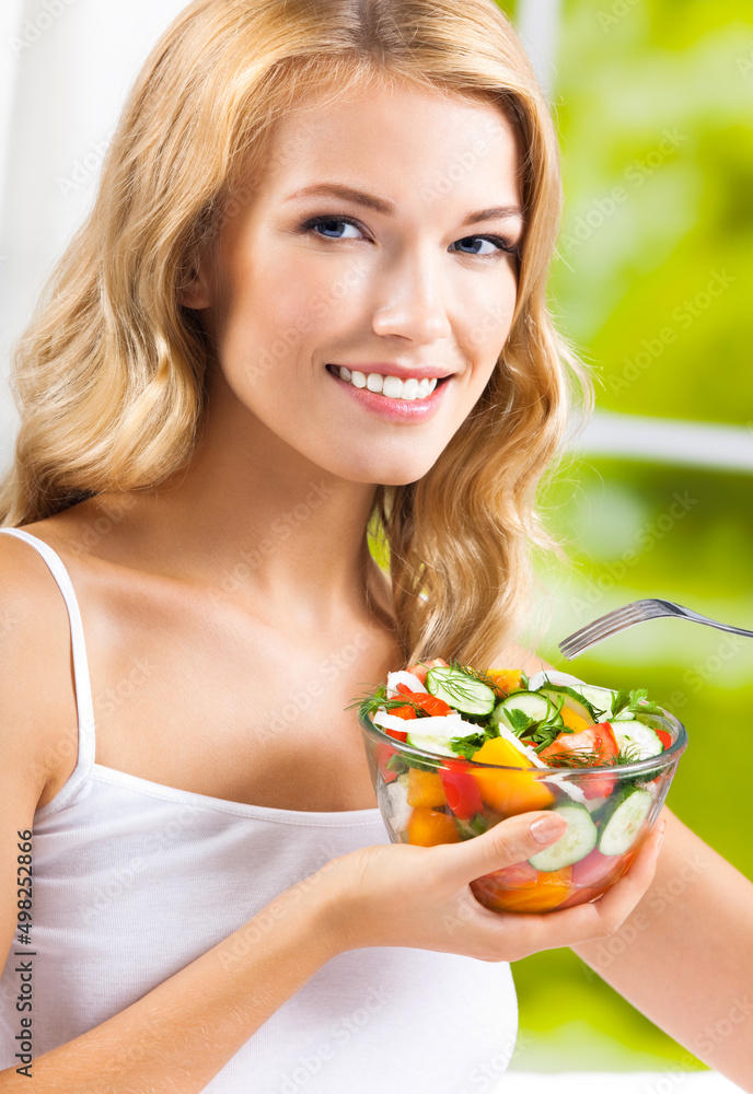 Portrait of happy smiling young woman with vegetable salad near window, indoors. Healthy eating, vegetarian, keto ketogenic diet concept. Portrait of happy smiling young woman with vegetable salad near window, indoors. Healthy eating, vegetarian, keto ketogenic diet concept.