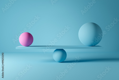 Big blue ball and small pink ball balancing on a scale. Power balance or harmony photo