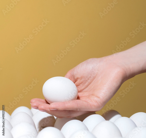 hand takes a white egg from the tray. Background for text Holiday Easter