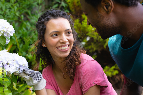 African american young couple looking at each other and smiling while gardening together in garden