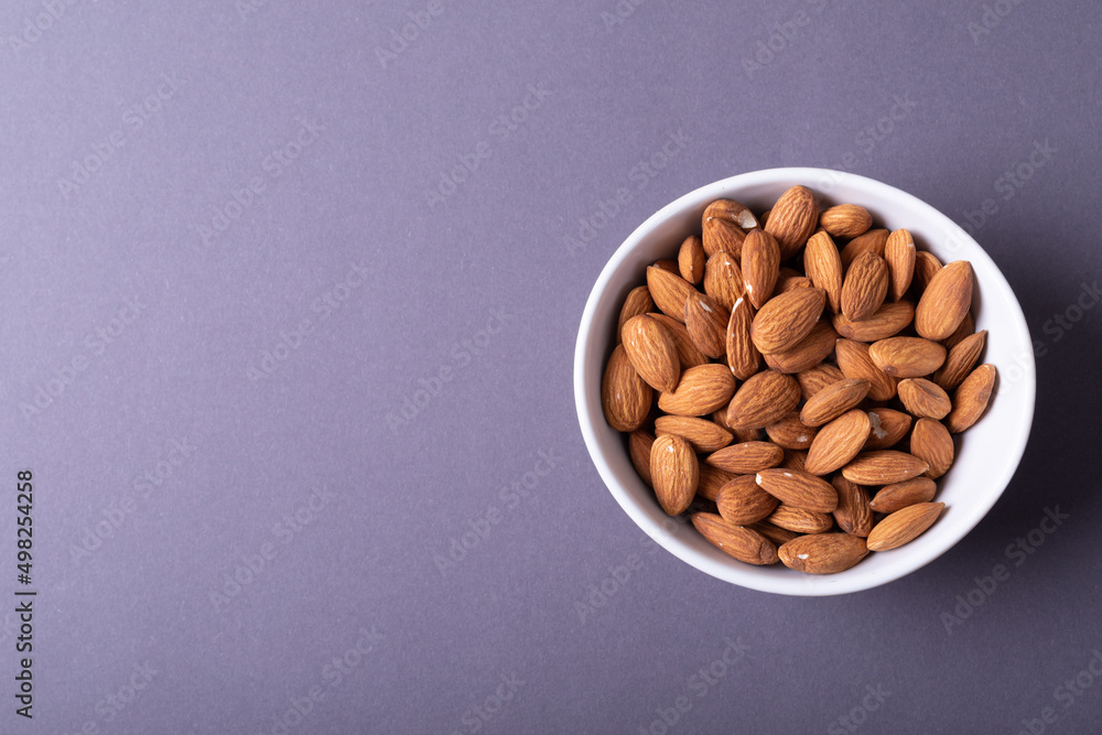 Directly above shot of almonds in bowl on gray background with copy space Directly above shot of almonds in bowl on gray background with copy space